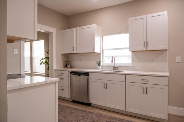 kitchen featuring decorative backsplash, light wood-type flooring, white cabinets, sink, and dishwasher