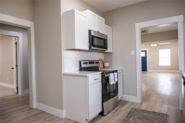 kitchen featuring tasteful backsplash, white cabinetry, stainless steel appliances, and light hardwood / wood-style flooring