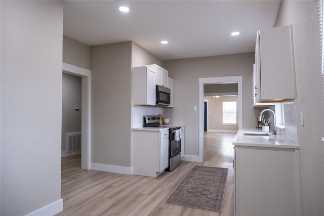 kitchen featuring sink, white cabinetry, stainless steel appliances, and light wood-type flooring