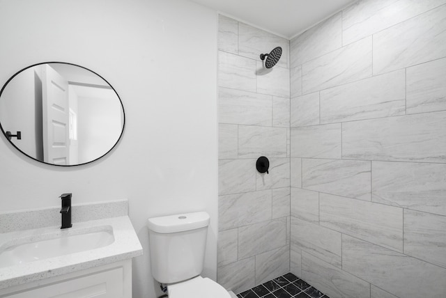 bathroom with toilet, vanity, and tiled shower