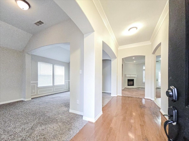 entryway with lofted ceiling, wood-type flooring, and ornamental molding