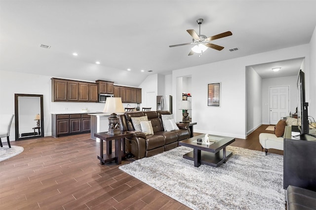 living room featuring vaulted ceiling, ceiling fan, and dark wood-type flooring