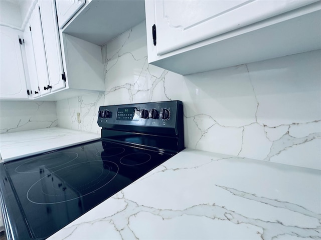 kitchen with light stone countertops, range with electric cooktop, and white cabinets