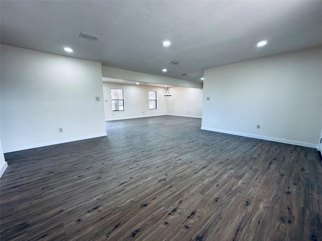 unfurnished living room featuring dark wood finished floors, visible vents, and baseboards