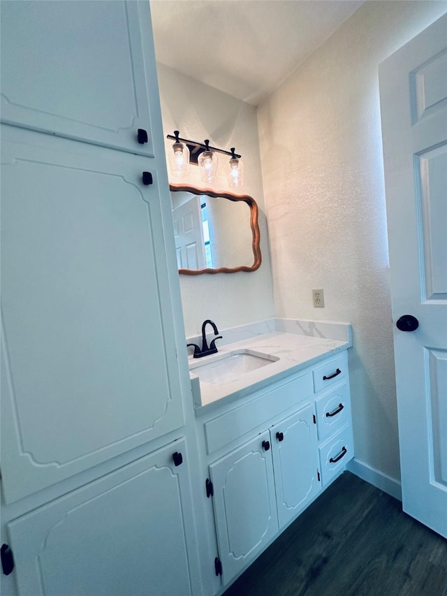 bathroom with wood finished floors, vanity, and baseboards