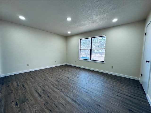 spare room featuring a textured ceiling, dark wood finished floors, and baseboards