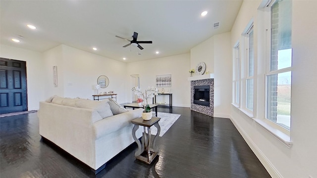 living room with a tile fireplace, dark hardwood / wood-style flooring, and ceiling fan