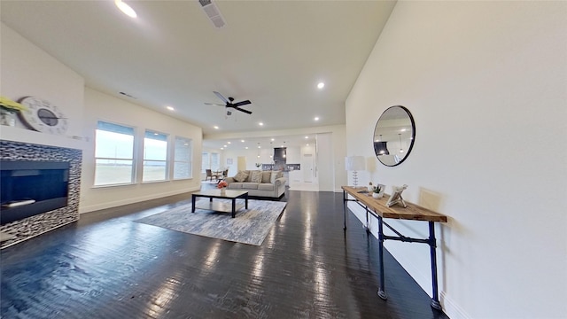 living room with a tile fireplace, dark hardwood / wood-style floors, and ceiling fan