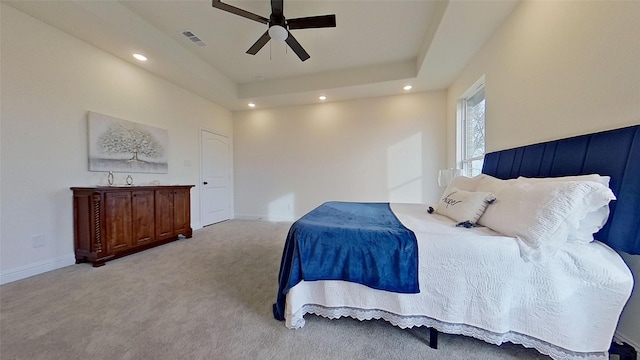 bedroom with light colored carpet, ceiling fan, and a tray ceiling