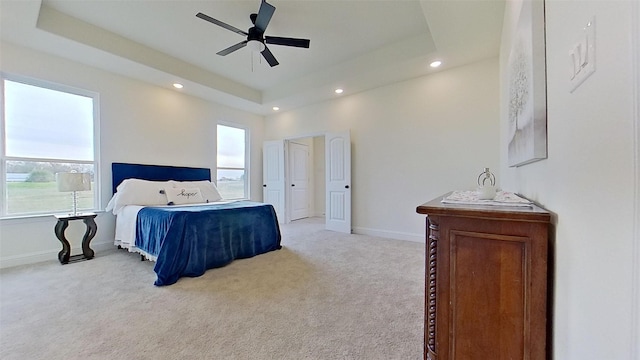 carpeted bedroom with a raised ceiling and ceiling fan