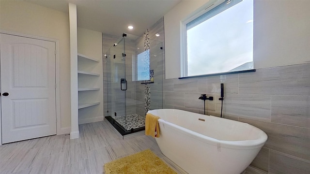 bathroom featuring shower with separate bathtub and tile walls