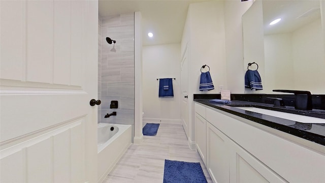 bathroom with tiled shower / bath combo and vanity