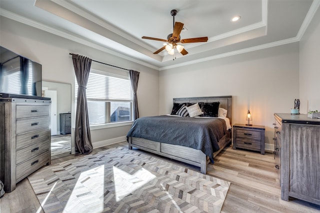 bedroom with ceiling fan, a raised ceiling, light wood-type flooring, and crown molding