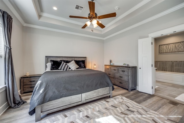 bedroom with ensuite bathroom, a raised ceiling, ceiling fan, light wood-type flooring, and ornamental molding