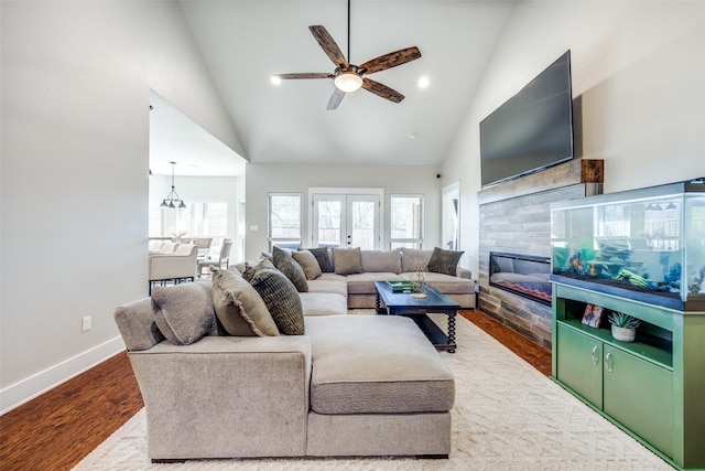 living room featuring ceiling fan, french doors, high vaulted ceiling, a tiled fireplace, and hardwood / wood-style flooring