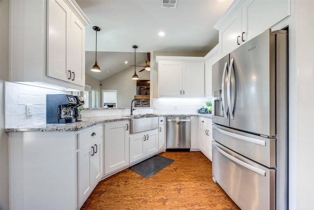 kitchen featuring tasteful backsplash, stainless steel appliances, hardwood / wood-style flooring, white cabinets, and lofted ceiling