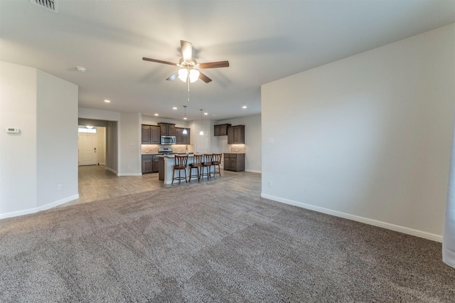 unfurnished living room featuring ceiling fan and carpet floors