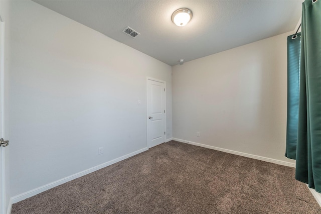 spare room featuring a textured ceiling, lofted ceiling, and dark colored carpet