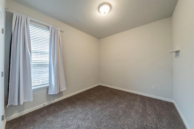 unfurnished room featuring dark colored carpet, a healthy amount of sunlight, and a textured ceiling