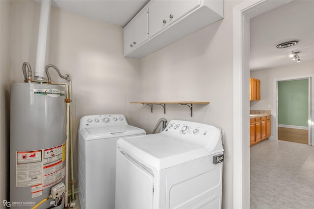 laundry area featuring water heater, washer and clothes dryer, and cabinets