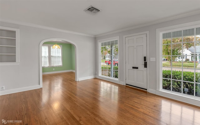 interior space featuring a wealth of natural light, hardwood / wood-style floors, and crown molding