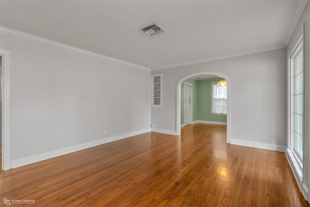 empty room featuring hardwood / wood-style flooring, crown molding, and a healthy amount of sunlight