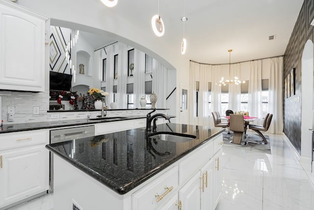 kitchen featuring sink, a notable chandelier, dark stone counters, decorative light fixtures, and a kitchen island