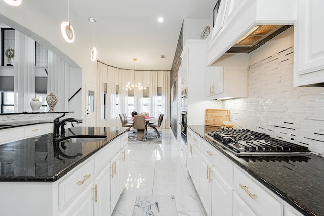 kitchen featuring dark stone countertops, sink, a healthy amount of sunlight, and decorative light fixtures