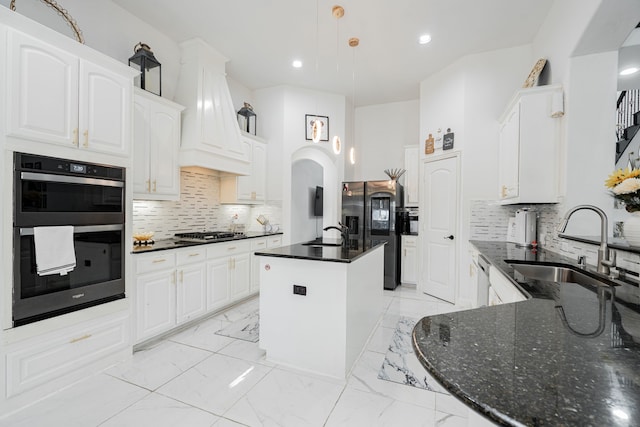 kitchen with appliances with stainless steel finishes, a center island with sink, white cabinetry, and sink