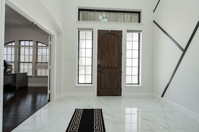 entryway with light wood-type flooring, ornamental molding, and a wealth of natural light