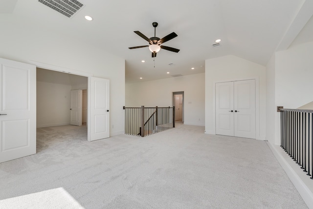 interior space featuring ceiling fan, light colored carpet, and vaulted ceiling