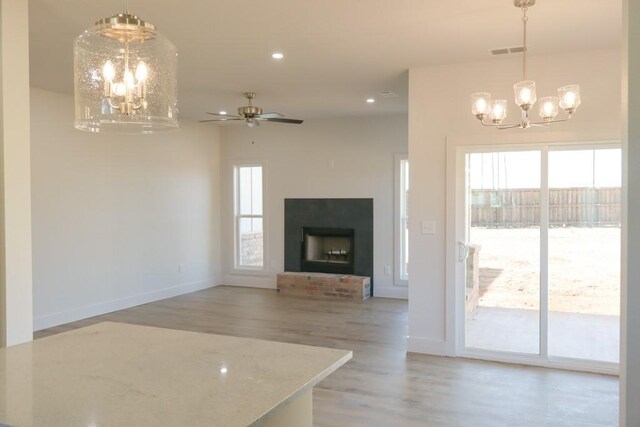 living room featuring ceiling fan with notable chandelier and a brick fireplace