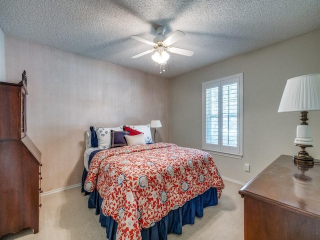 bedroom with ceiling fan, light carpet, and a textured ceiling