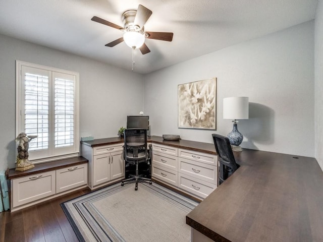 home office with dark wood-type flooring, built in desk, and ceiling fan