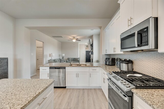 kitchen featuring decorative backsplash, appliances with stainless steel finishes, light wood-type flooring, and white cabinetry