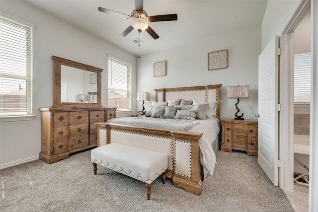 bedroom featuring ceiling fan, light colored carpet, and ensuite bathroom