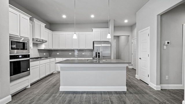 kitchen with appliances with stainless steel finishes, decorative light fixtures, white cabinets, dark hardwood / wood-style floors, and an island with sink