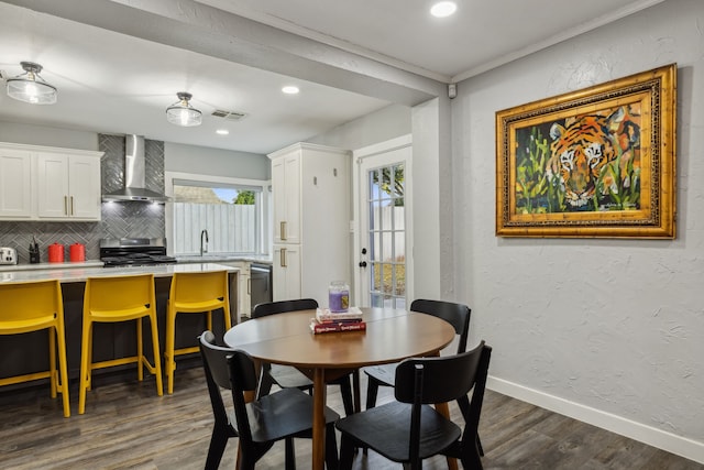 dining space featuring dark hardwood / wood-style floors, ornamental molding, and sink