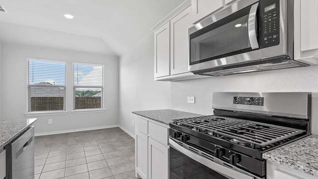 kitchen featuring light tile patterned flooring, appliances with stainless steel finishes, white cabinetry, and light stone counters