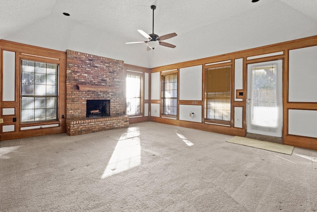 unfurnished living room with a brick fireplace, a wealth of natural light, lofted ceiling, and ceiling fan