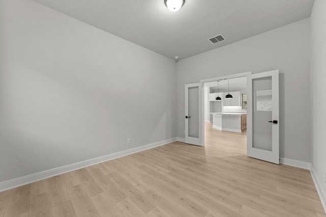 spare room with light wood-style flooring, french doors, baseboards, and visible vents