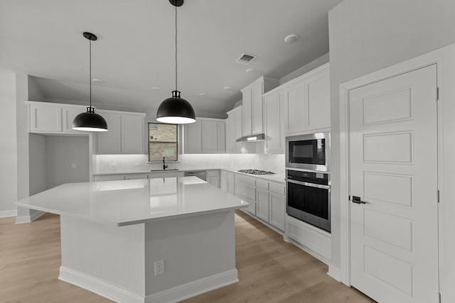 kitchen with a kitchen island, light wood-style floors, visible vents, appliances with stainless steel finishes, and a sink