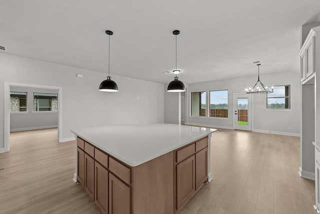 kitchen with light wood-style flooring, a center island, light countertops, brown cabinets, and hanging light fixtures