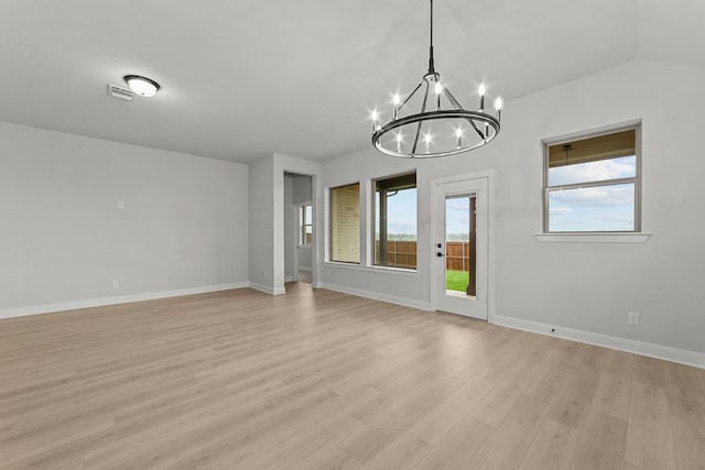 spare room with baseboards, an inviting chandelier, light wood-style floors, visible vents, and lofted ceiling
