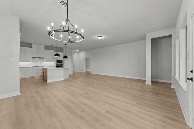 unfurnished living room featuring a chandelier, visible vents, light wood-type flooring, and baseboards