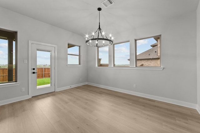unfurnished dining area with a notable chandelier, visible vents, light wood-type flooring, and baseboards
