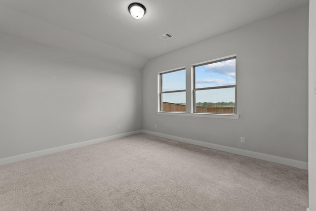 carpeted empty room with visible vents, baseboards, and lofted ceiling