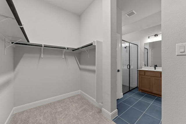 walk in closet featuring a sink, visible vents, and dark carpet