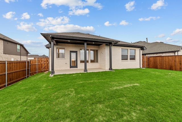 rear view of house with brick siding, a fenced backyard, a patio area, and a lawn