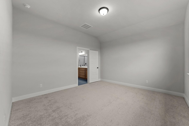 unfurnished bedroom featuring baseboards, vaulted ceiling, ensuite bath, carpet floors, and visible vents